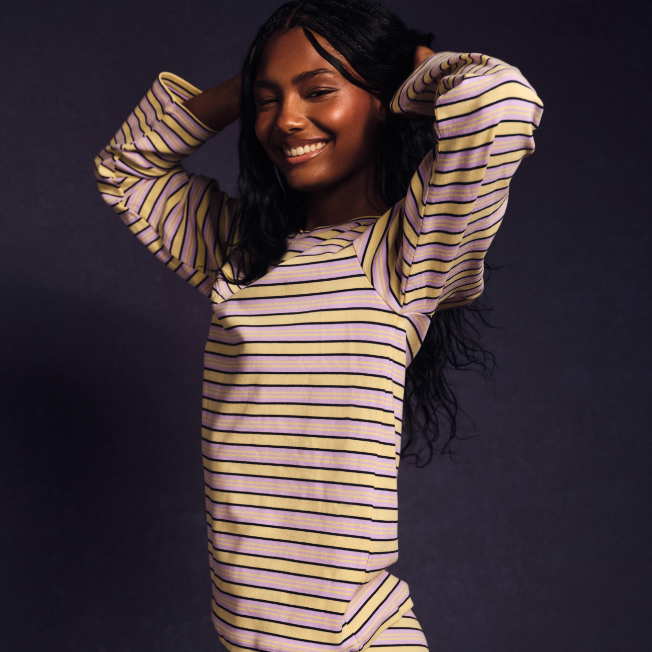 Woman wearing a striped outfit against a dark background