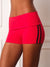 A close-up of a model wearing bright red athletic shorts with a wide waistband and black side stripes, shown against a light neutral indoor background. <model-info>Courtney wears a size S and is 5’8”, 25” waist, 32B bust.</model-info>
