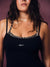 A close-up of a woman wearing a black tank top with zebra-print trim along the neckline and the word 'SET' printed in white on the chest, against a mauve background.