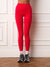 A person wearing bright red high-waisted leggings, white socks, and gray running shoes, standing against a white paneled wall on a wood floor.