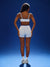 Person wearing a white sports bra and shorts on a blue background