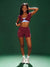 Woman wearing a maroon athletic outfit on a green background