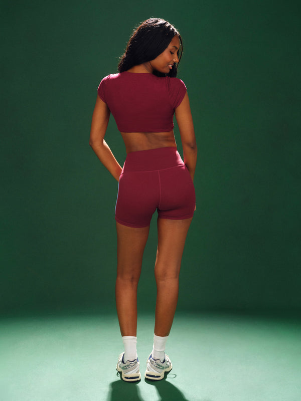 Woman wearing a maroon athletic outfit on a green background