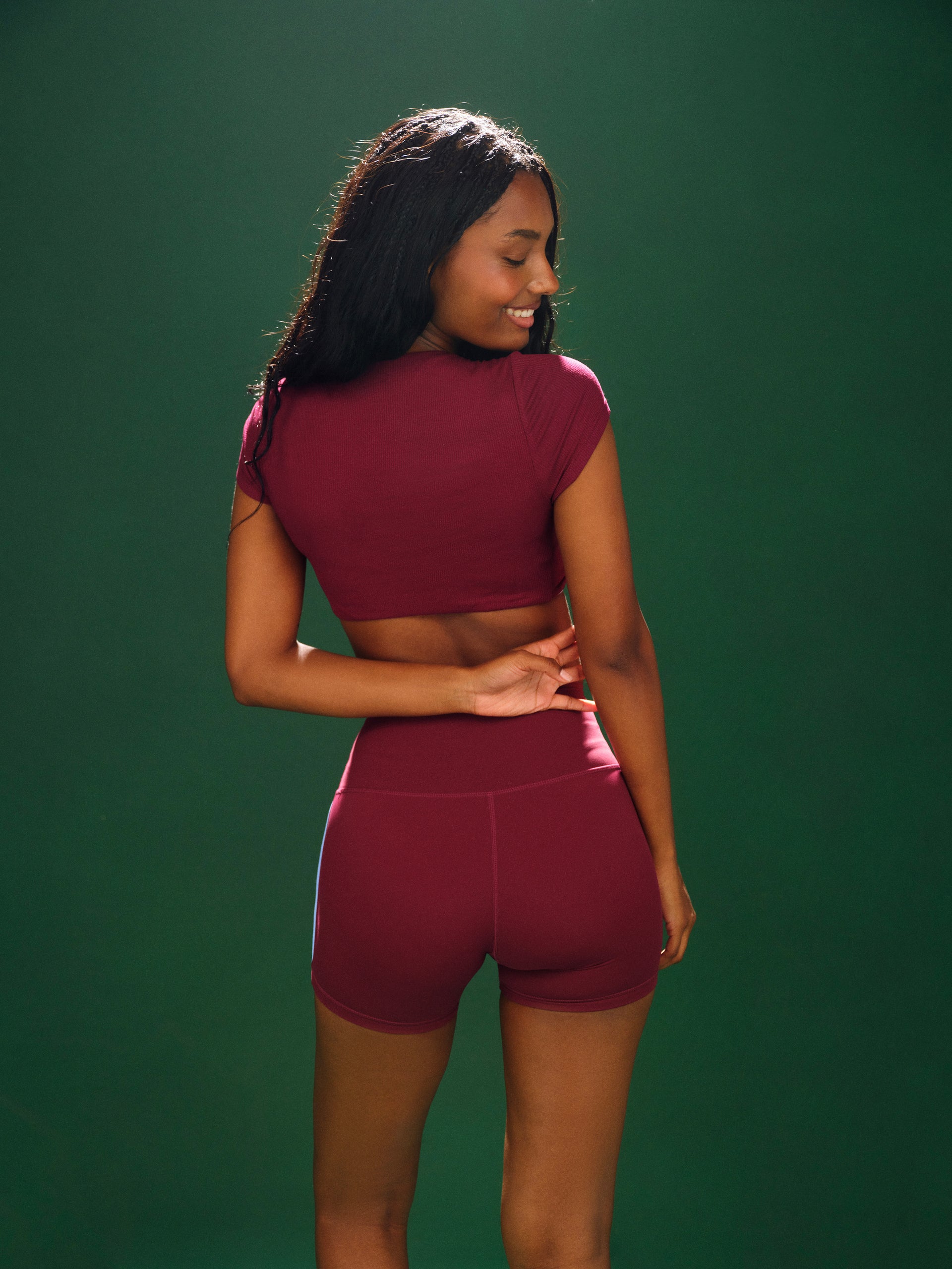 Woman wearing a maroon athletic outfit against a green background
