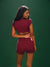 Woman wearing a maroon athletic outfit against a green background