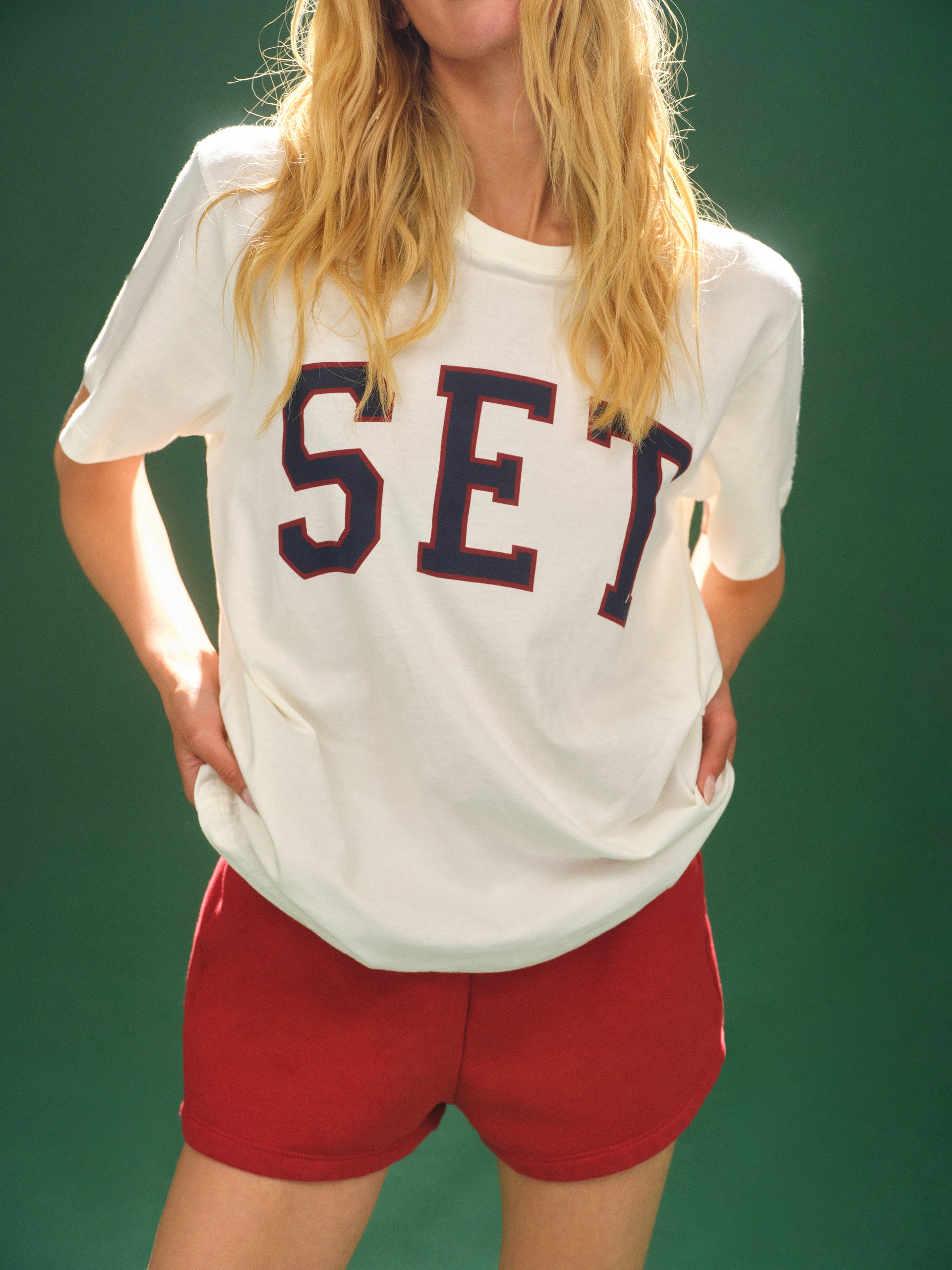 Person wearing a white t-shirt with 'SET' printed on it against a green background