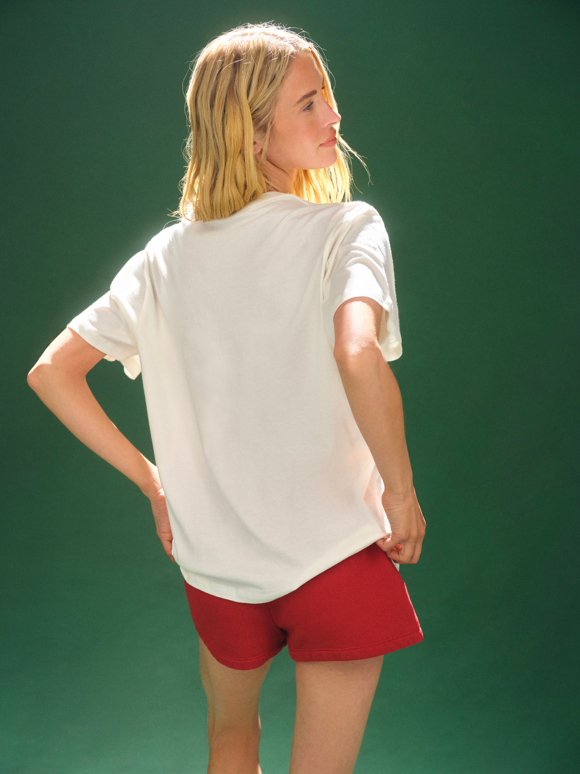 Person wearing a white t-shirt and red shorts against a green background