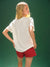 Person wearing a white t-shirt and red shorts against a green background