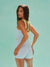 Woman wearing a light blue romper with yellow straps against a light green background
