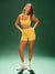 Woman wearing a yellow sports outfit on a green background