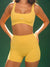 Person wearing a yellow sports bra and shorts set with 'SET' branding on a green background