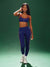 Woman wearing a blue athletic outfit on a green background <model-info>Umi wears a size XS and is 5’8½”, 23½” waist, 32B bust.</model-info>