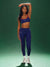 Woman wearing a blue sports bra and leggings on a green background