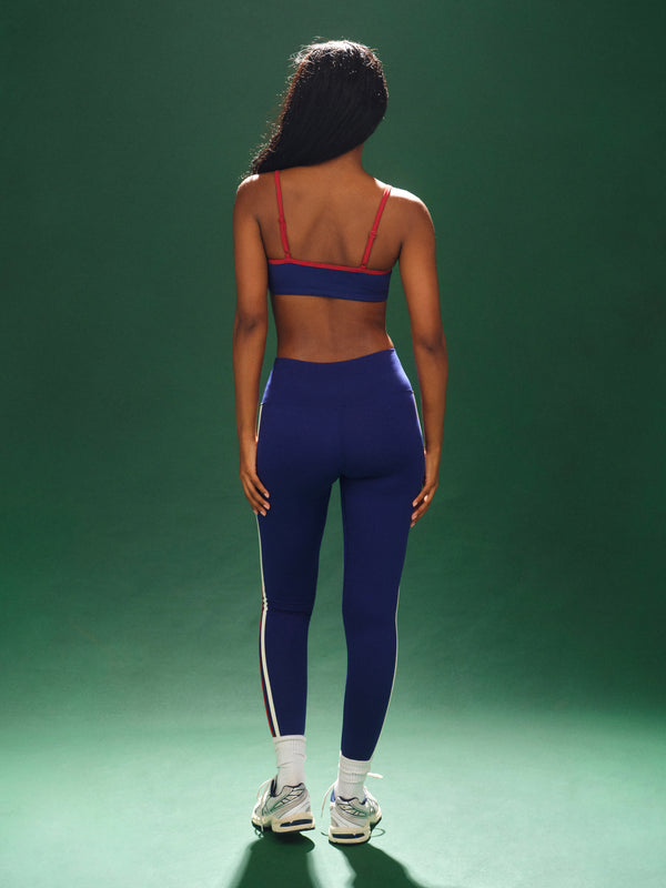 Person wearing a blue athletic outfit with red accents on a green background