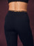 Close-up back view of a model wearing black high-waisted leggings with a leopard-print waistband, paired with a matching black sports bra.