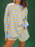 Person wearing a blue and yellow striped long-sleeve top and shorts on a green background