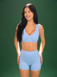 Front of Aeraline Breathe Hamptons Bra in Popsicle with contrast piping and breathable fabric on model on green background