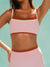 Person wearing a pink sports bra with a brand logo on a light blue background