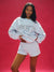 Person wearing a light gray 'SET' sweatshirt and shorts on a red background <model-info>Umi wears a size S and is 5’8½”, 23½” waist, 32B bust.</model-info>