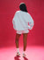 Person wearing a light blue sweatshirt and shorts on a red background