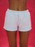 White shorts worn by a person on a red background <model-info>Umi wears a size S and is 5’8½”, 23½” waist, 32B bust.</model-info>
