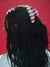 Person with braided hair wearing a striped headband against a red background