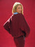 Person wearing a burgundy tracksuit against a red background