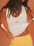 Woman wearing a white sports bra with 'SET' branding against an orange background <model-info>Jocelyn wears a size S and is 5'9, 23” waist, 32B bust.</model-info>