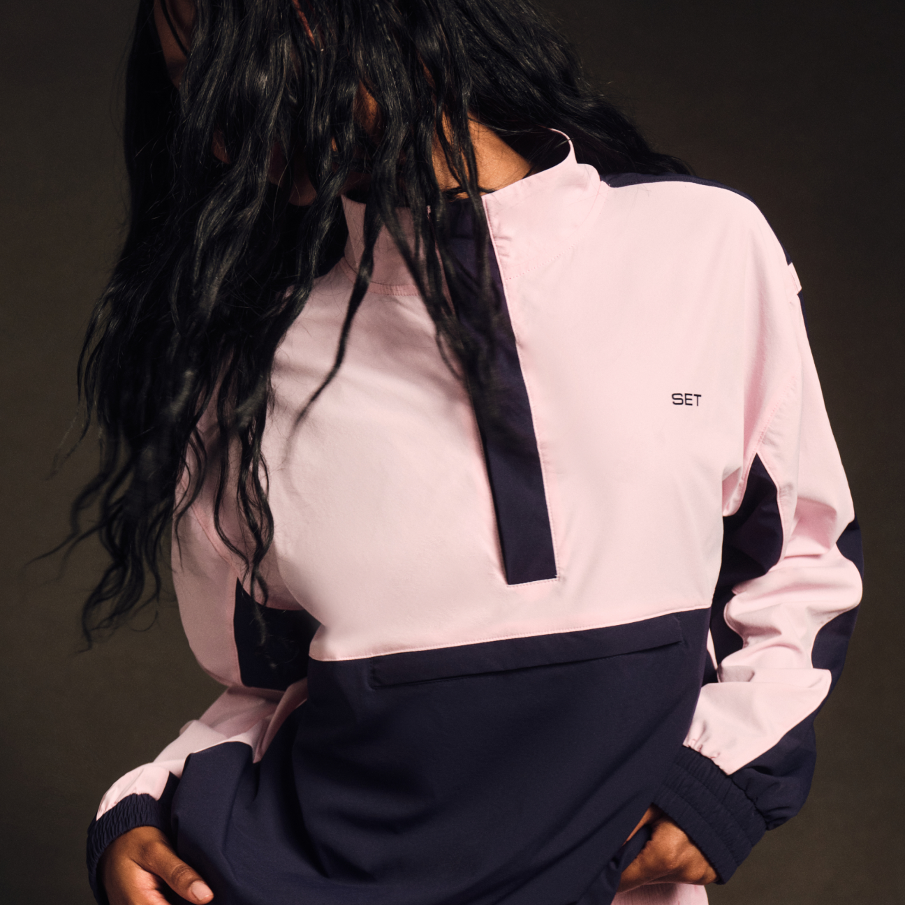 Person wearing a pink and navy outfit with 'SET' branding on a dark background