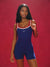 Woman wearing a blue and red jumpsuit against a red background <model-info>Umi wears a size XS and is 5’8½”, 23½” waist, 32B bust.</model-info>