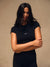 A woman modeling a black short-sleeve athletic crop top with a small white 'SET' logo on the chest, paired with black leggings, against a neutral beige studio background.