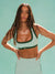 Woman wearing a sports bra and leggings with a light green background <model-info>Logan wears a size XS and is 5’9½”, 24” waist, 32B bust.</model-info>