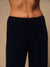 Close-up of a person wearing dark navy ribbed knit drawstring pants against a warm beige studio background.