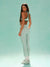 Woman wearing a green sports bra and white leggings on a light blue background
