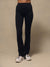 Black high-waisted athletic leggings worn by a model, paired with white sneakers, photographed against a neutral beige studio backdrop.