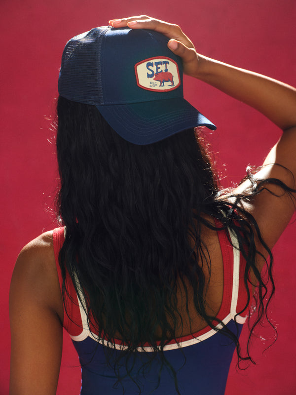 Person wearing a blue cap with a logo against a red background