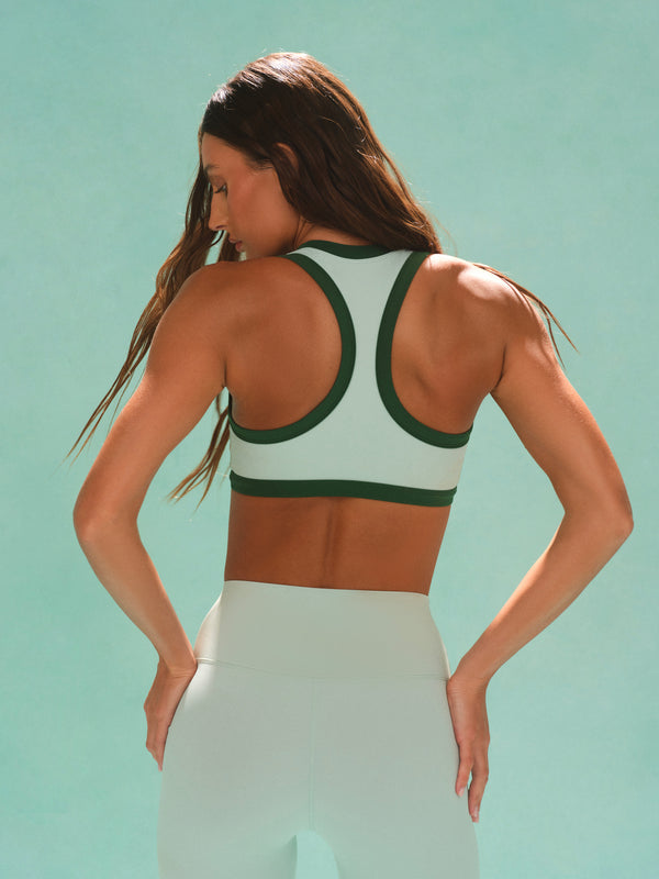 Woman wearing a green and white sports bra against a light blue background