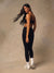 A woman posing in a black sports bra and black leggings with white socks and white sneakers, set against a textured beige studio backdrop.