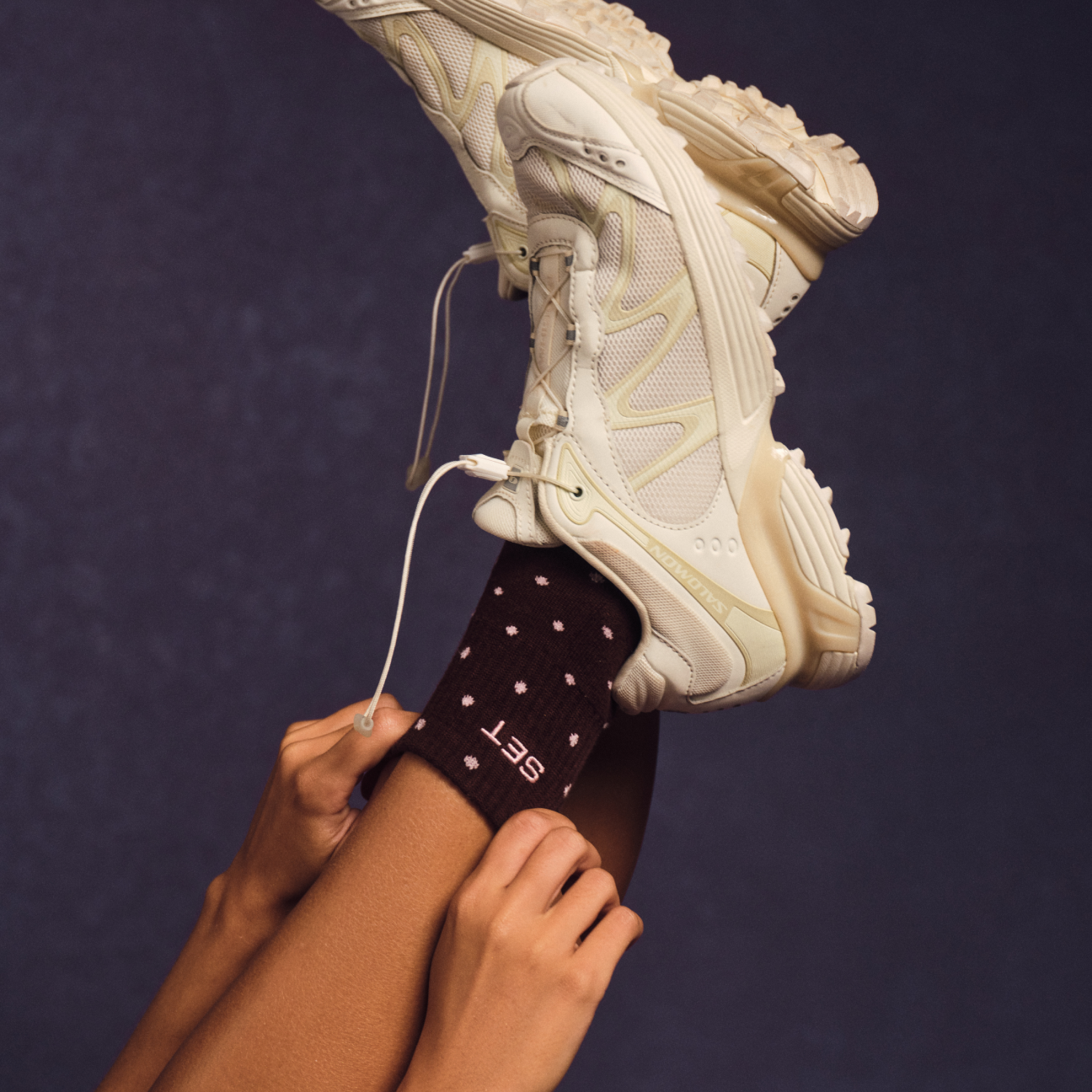 Person wearing a white sneaker with a dark background