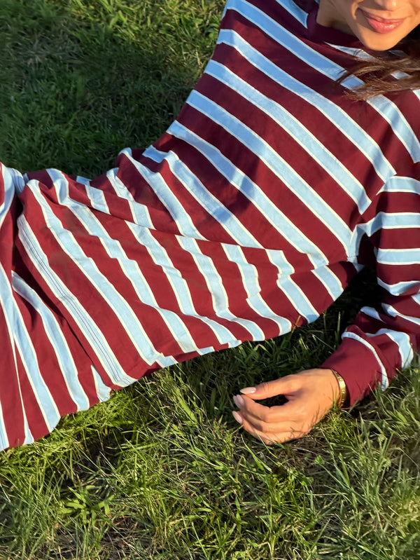 Person wearing a red and white striped shirt sitting on grass