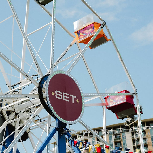 Ferris wheel with colorful cabins against a blue sky, featuring the 'SET' logo.