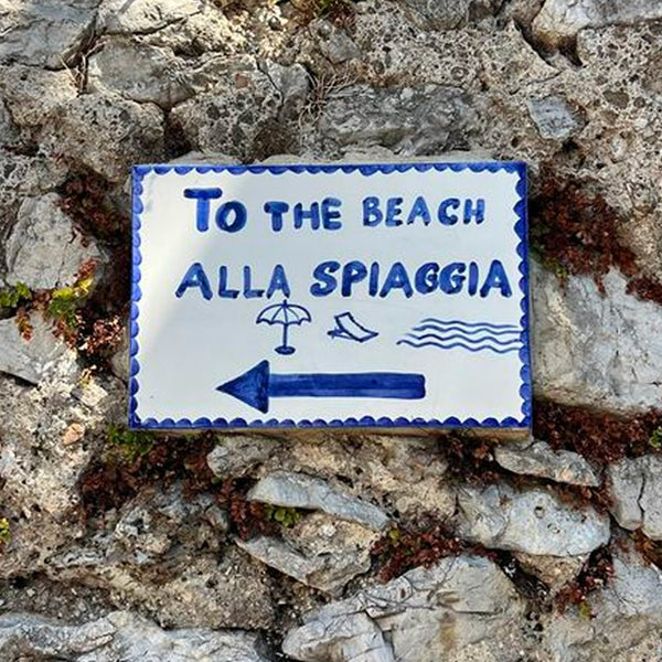Sign with blue letters against a rock.