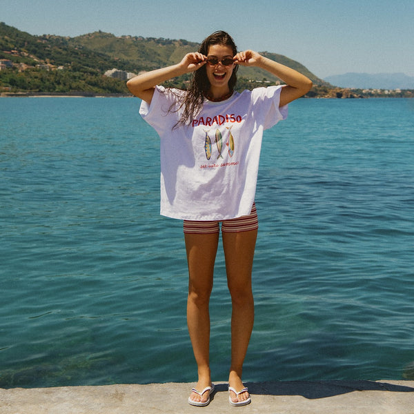 Woman wearing an oversized t-shirt standing by the water.