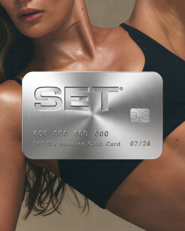 Silver credit card with 'SET' brand logo and a woman in a sports bra in the background 