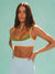 Woman wearing a sports bra and leggings against a light green background