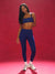 Woman wearing a blue sports bra and leggings on a red background