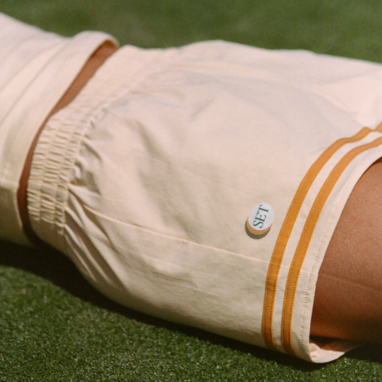 Beige shorts with brown and orange stripes on a green grass background