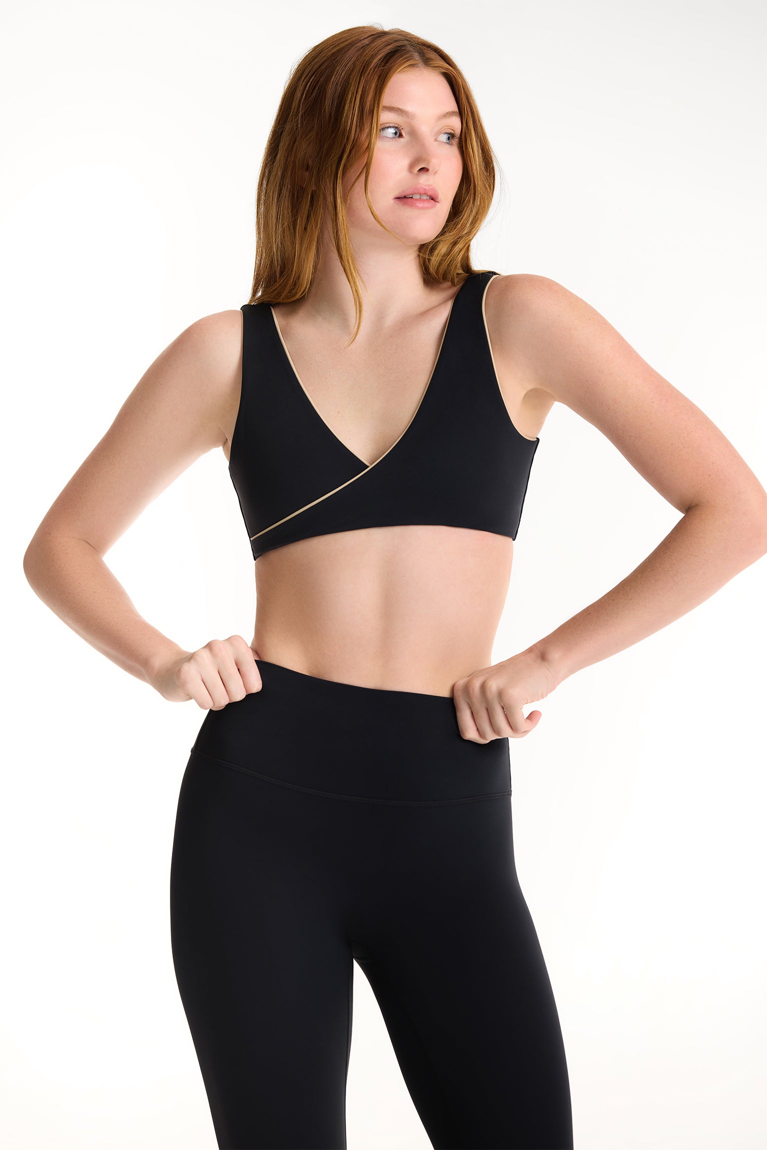 Woman wearing a black sports bra and leggings on a white background 