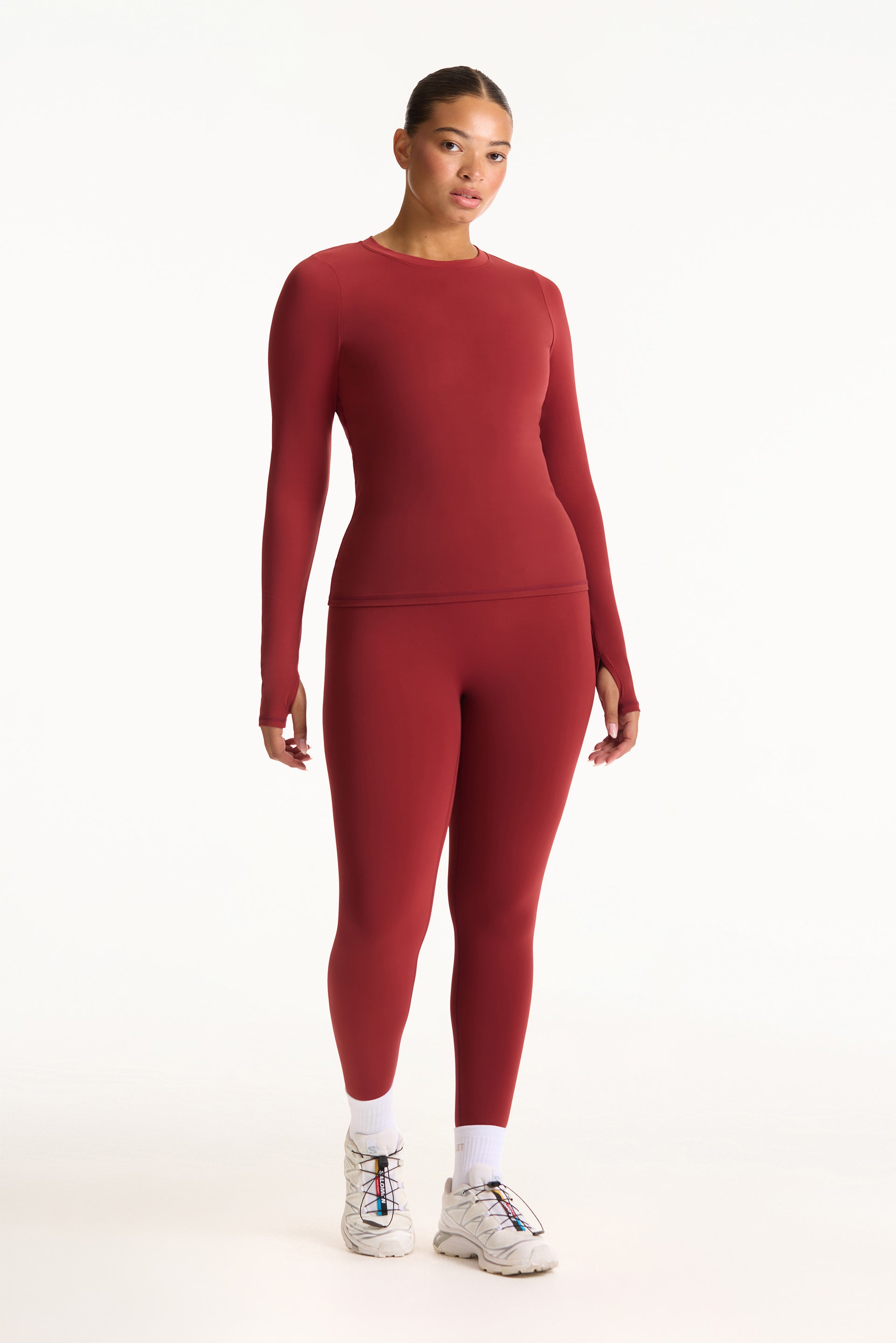 Person wearing a red long-sleeve top and leggings on a white background