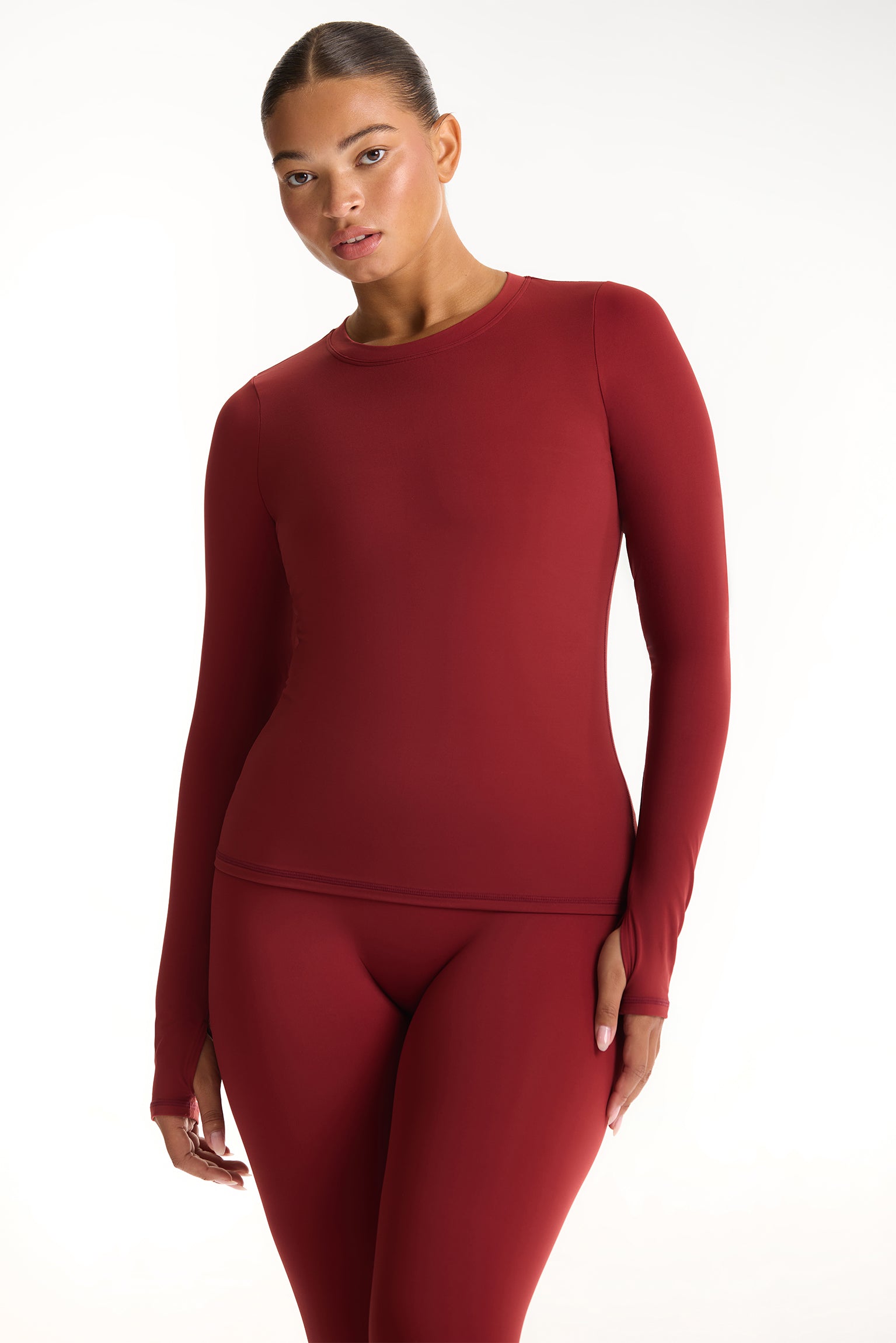 Woman wearing a red long-sleeve top and leggings on a white background <model-info>Jade wears a size L and is 5’9”, 30” waist, 38” bust.</model-info>